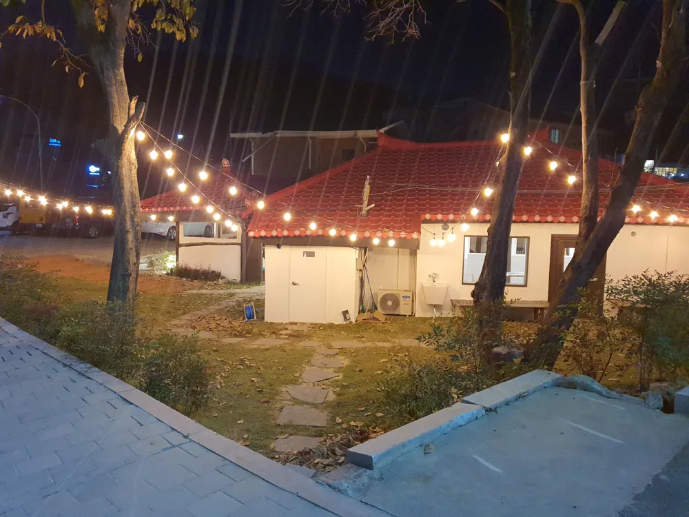 전구 조명이 걸린 마당과 기와 건물 시공 완료 실제 사진